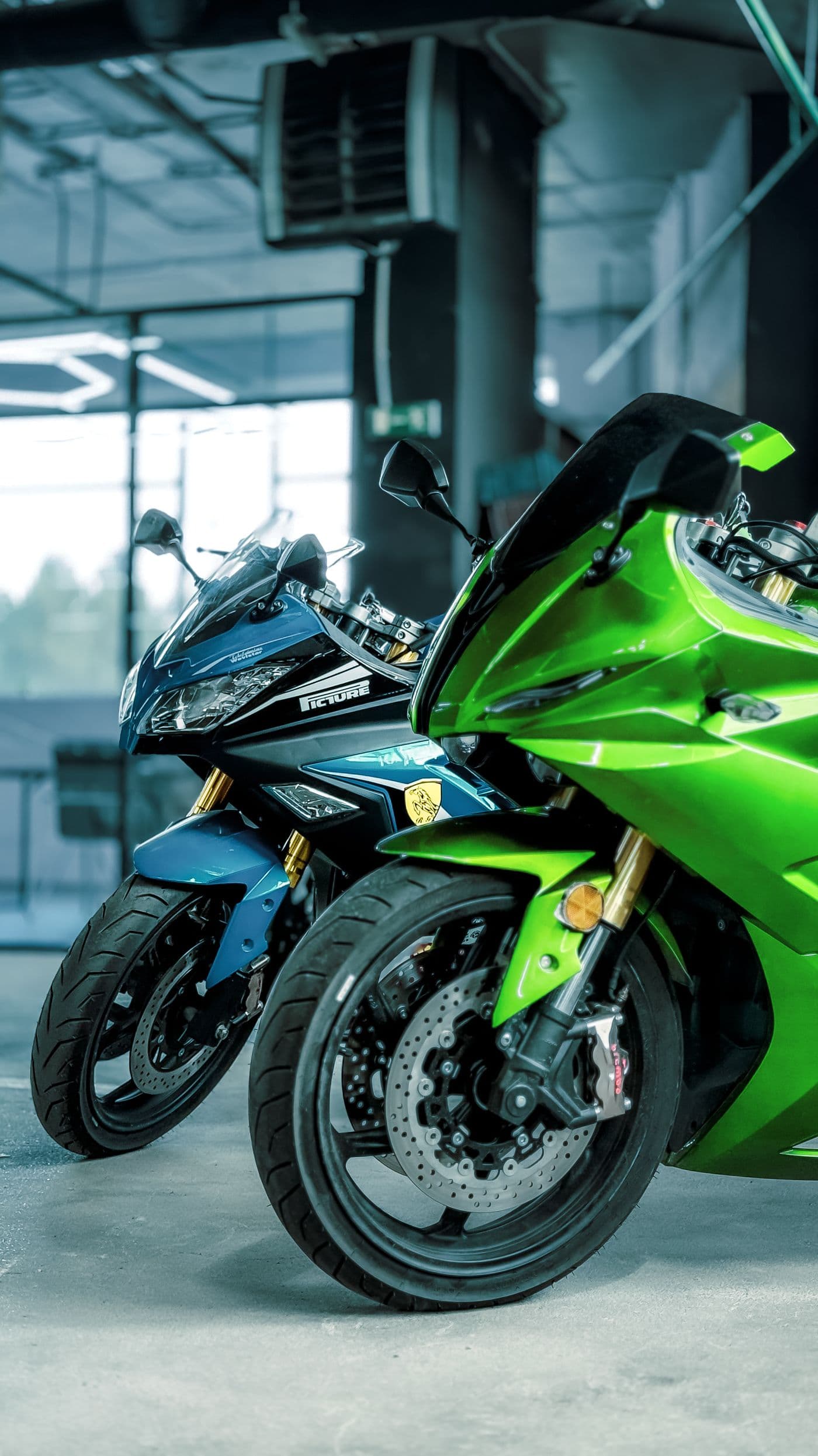 Moto deportiva verde de perfil junto a un muro