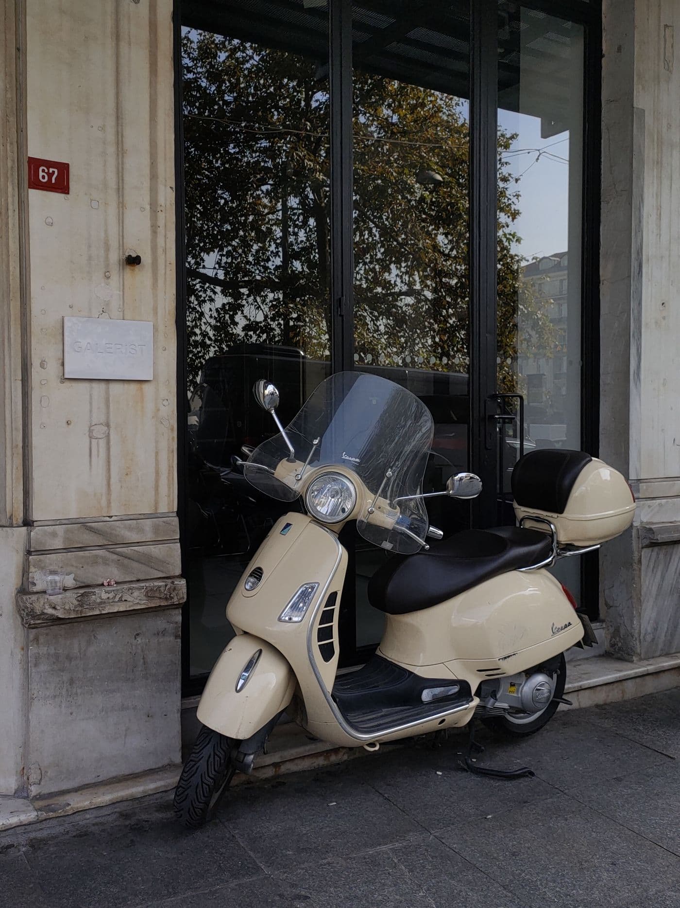 Scooter clásico aparcado frente a un portón de madera